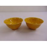 A pair of Chinese yellow ground tea bowls, marks to the bases