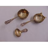 A silver caddy spoon and two silver tea strainers with stands