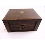 A rectangular oak flatware case with fitted interior, hinged top with two drawers