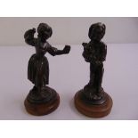 A pair of bronze figurines of a country boy and girl on raised circular plinths