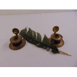 A pair of brass and blue glass circular inkwells and a quill pen