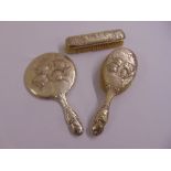 A silver mounted hand mirror chased with putti, a matching hair brush and a matching clothes brush