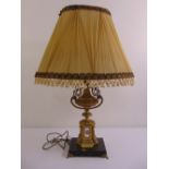 A gilded metal table lamp on raised octagonal base with applied porcelain panels and silk shade