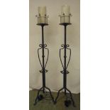 A pair of painted wrought iron candle holders converted to electricity on three scroll supports