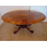 A Victorian oval inlaid walnut tilt top hall table on four outswept legs with original casters