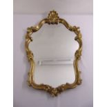 A shaped oval gilded wooden Rococo style wall mirror