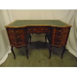 An Edwardian shaped rectangular mahogany kneehole desk with tooled leather top, brass handles, on