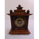 An oak cased French mantle chiming clock with gilt and enamel decoration on stepped square base