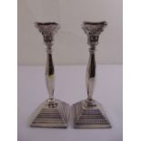 A pair of Corinthian column silver filled table candlesticks, panelled oval stems on stepped