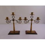 A pair of brass three light candelabra with scrolling arms on rectangular bases