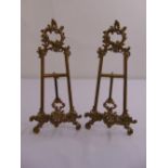 A pair of gilded metal scroll pierced table top picture easels with hinged struts