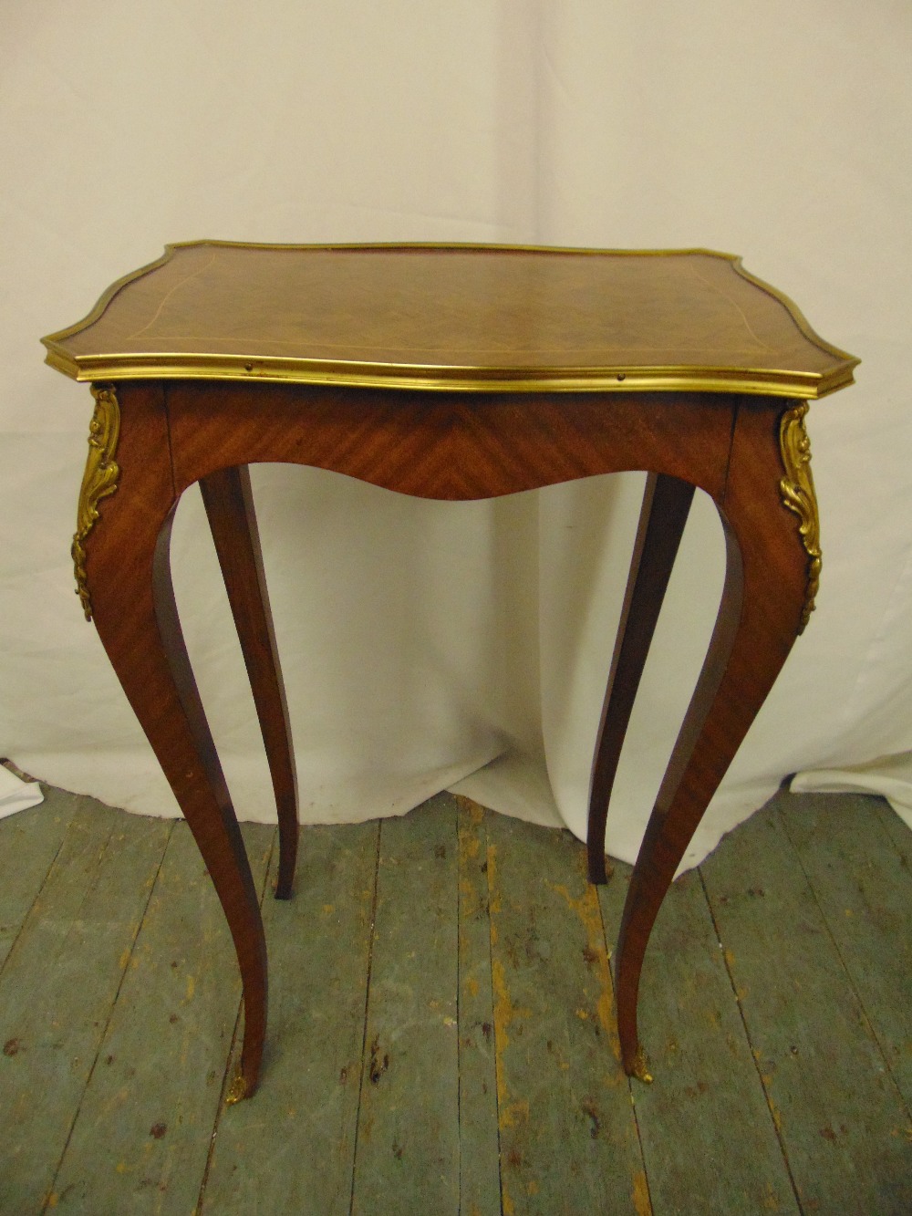 A rectangular Kingswood side table with applied gilded metal mounts on four cabriole legs