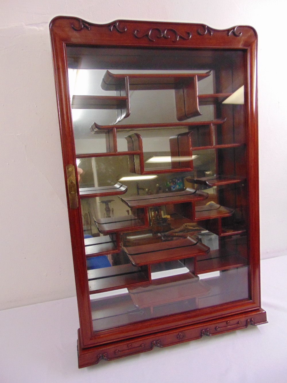 A wall mounted Oriental style miniatures display cabinet with mirrored back