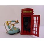 A modern telephone mounted in a red miniature telephone box and a 1980 decorative BT telephone