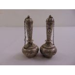 A pair of Indian white metal condiments, tapering cylindrical on compressed spherical bodies with