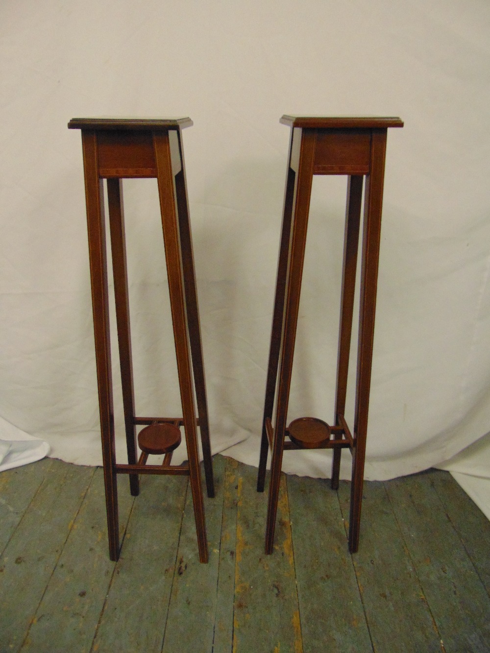 A pair of Edwardian mahogany inlaid plant stands on four tapering rectangular supports