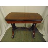 A Victorian mahogany rectangular games table, hinged top on scrolling supports
