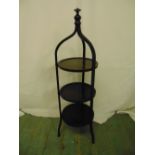 A three tier mahogany tea stand surmounted by baluster finial on three scrolling legs