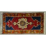 A Turkish red and blue ground rug, with floral border, 6' 3" x 3' 2"