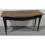 An Edwardian mahogany serpentine front serving table, with carved frieze, raised on turned and