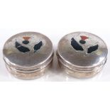 A pair of circular silver pillboxes, with Scottish thistle design hardstone set lids, by William