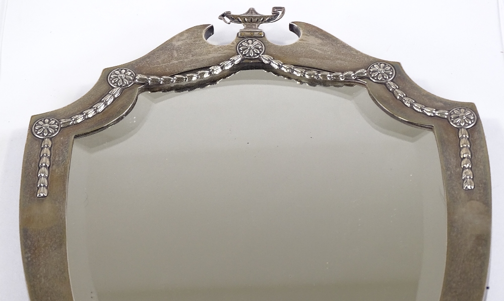 An Edwardian large silver-fronted shield-shaped mirror, with cup finial and silver foliate swags, by