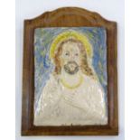 A Continental faience pottery relief moulded icon, height 22cm, mounted on wooden plaque, overall