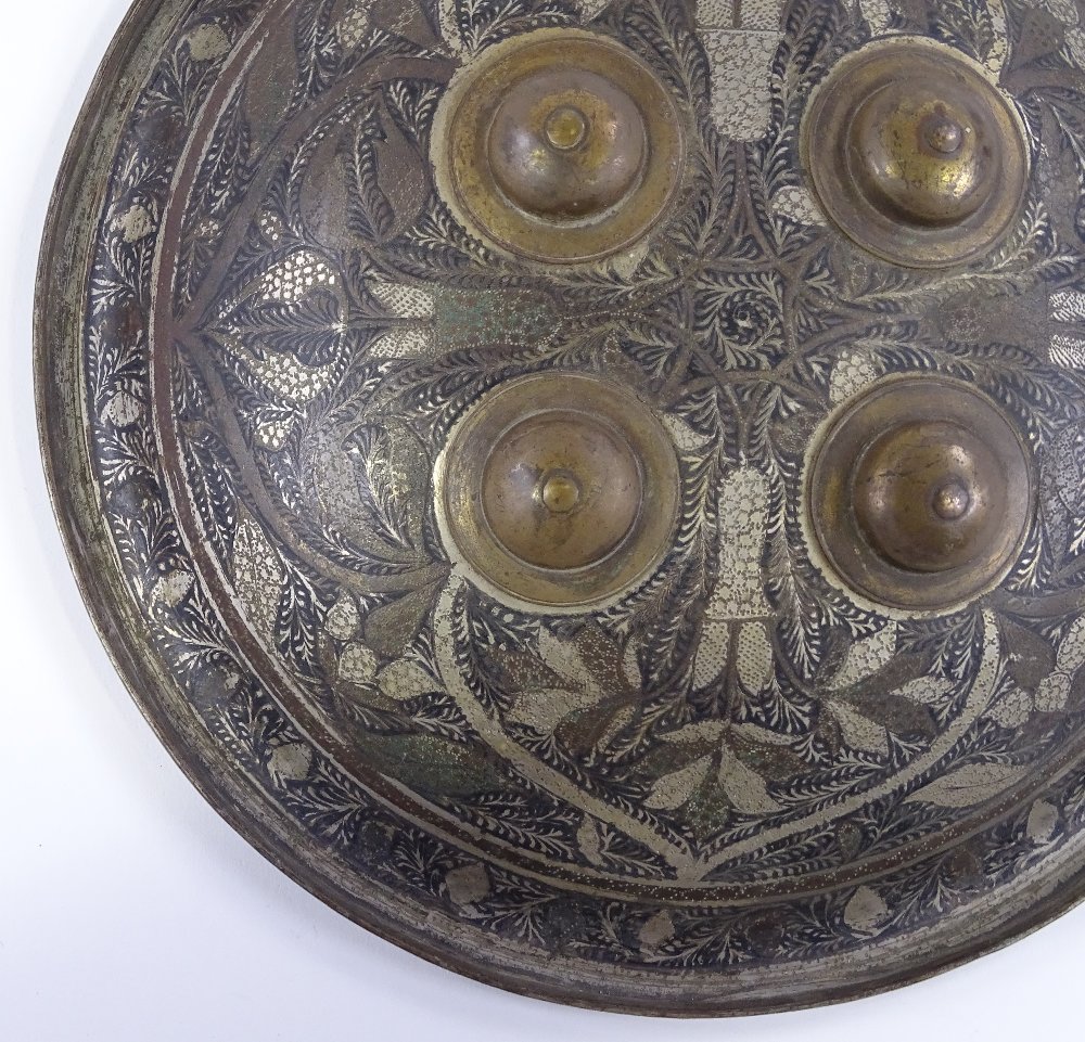 A 19th century Islamic metal shield, with inlaid floral decoration and brass bosses, diameter 26cm