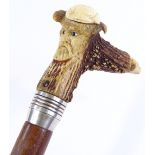 A walking stick with carved mask decorated horn handle