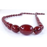 A string of graduated cherry amber beads, with screw clasp, largest bead length 32mm, 80.6g