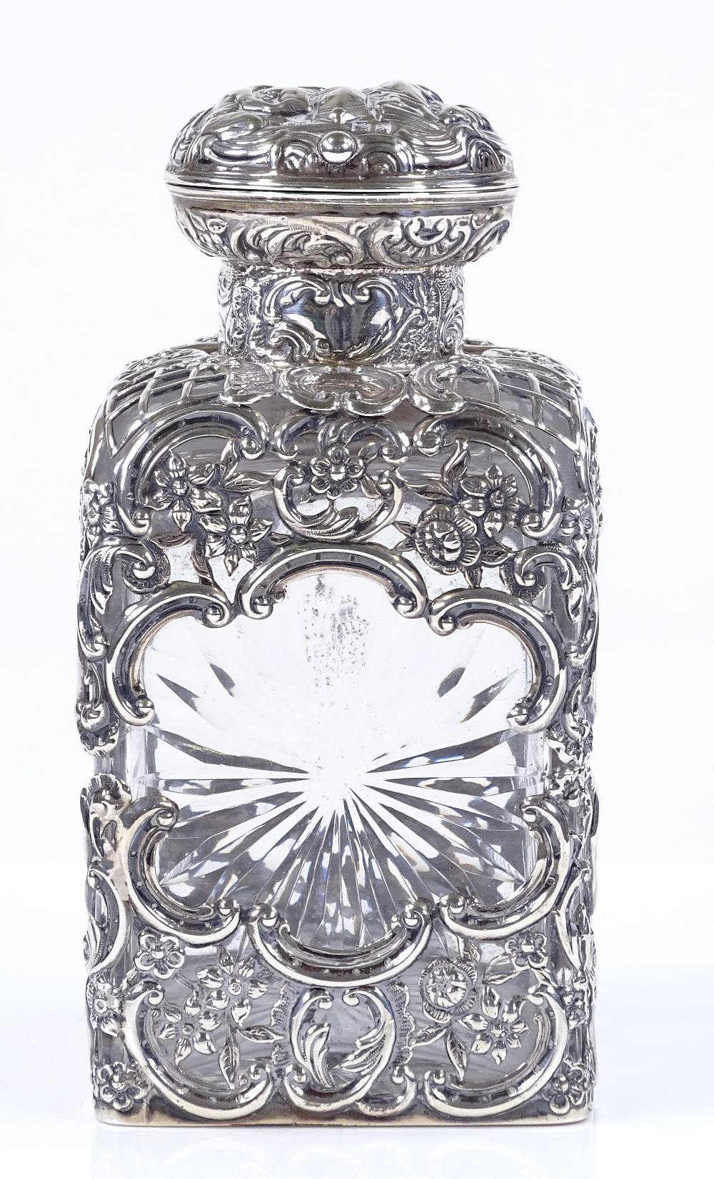 A late Victorian silver-mounted square cut-glass scent bottle, with pierced and relief embossed