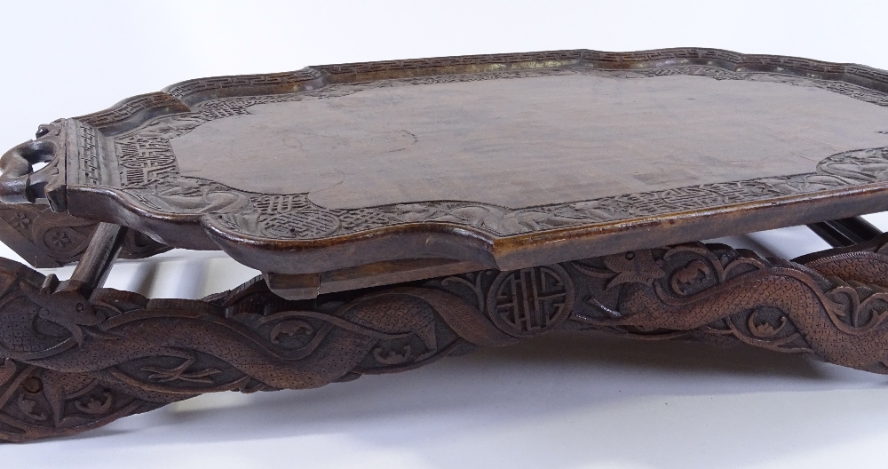 A Chinese hardwood 2-handled tea tray on folding stand, with relief carved dragon and symbolic - Image 3 of 3