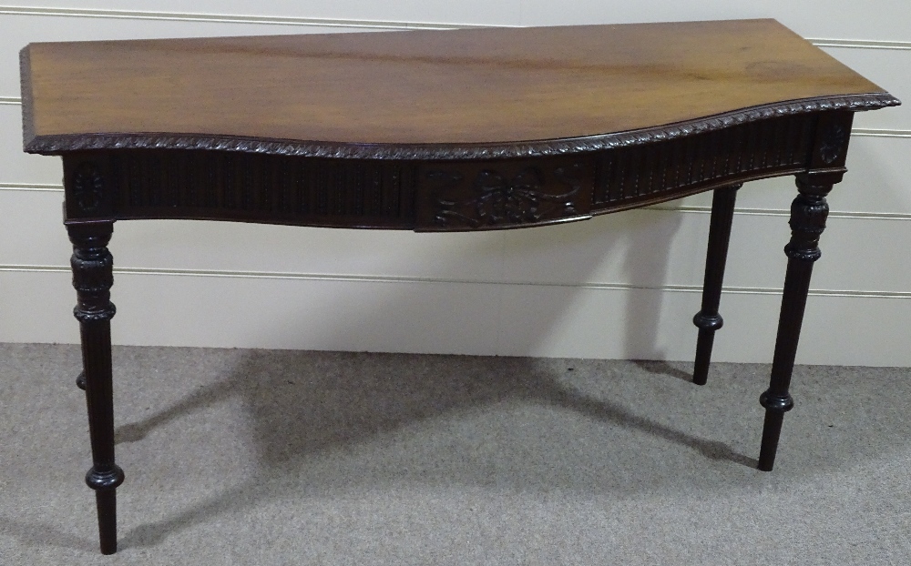 An Edwardian mahogany serpentine front serving table, with carved frieze, raised on turned and