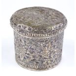 An ornate unmarked Indian silver cylindrical box, relief embossed floral decoration, height 7cm, 3.