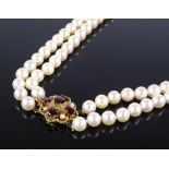 A standard short double-row pearl necklace, with 9ct gold garnet and seed pearl set open-work clasp,