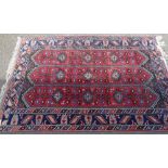 A large red and blue ground rug, with abstract border, 9'10" x 6'8"