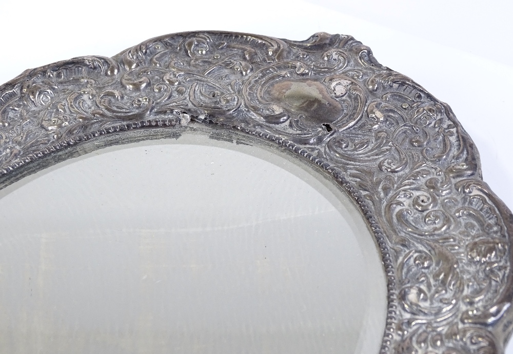 An Edwardian silver-fronted photo frame, with all over relief embossed foliate and scrollwork