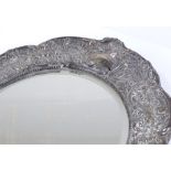 An Edwardian silver-fronted photo frame, with all over relief embossed foliate and scrollwork