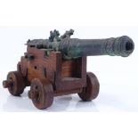 A patinated bronze model cannon on wooden wheeled carriage base, label under base "The Swedish