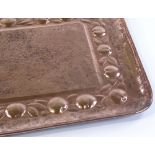 A Newlyn Arts and Crafts rectangular copper tray, with relief embossed fruit decorated border,