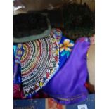 A box of textiles, including an African beadwork panel, a peacock feather headdress, silk table