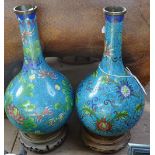 A pair of Japanese early 20th century cloisonne enamel narrow-necked vases on hardwood stands,