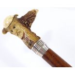 A walking stick with carved mask decorated horn handle
