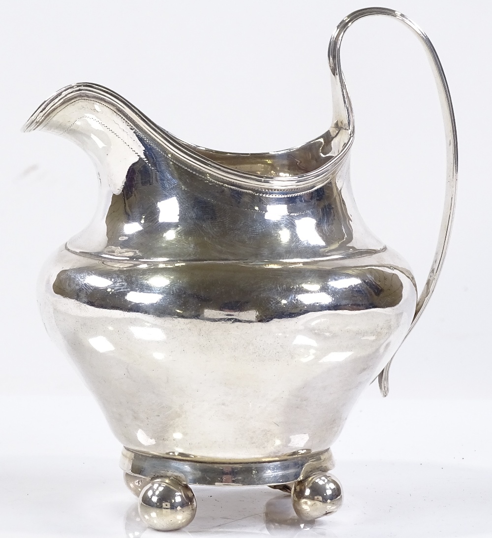 A silver bulbous cream jug, with reeded handle and bun feet, indistinct hallmarks, height 12cm, 4oz