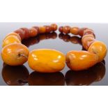 A string of large graduated amber beads, largest bead length 32.6mm, necklace length 510mm, 98.3g