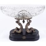 A cut-glass table centre bowl supported by electroplate mermaid figures, on ebonised plinth,