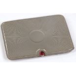 A rectangular silver double-stamp case, with sliding action, garnet setting and sunburst decoration,