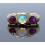 An 18ct gold 3-stone opal and star ruby ring, set with cabochon white opal, flanked by two