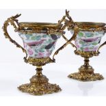 A pair of ornate ormolu and porcelain 2-handled urns, with hand painted bird and floral
