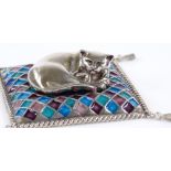 A modern Sarah Jones silver model of a cat on a coloured enamel cushion, with hanging corner tassels